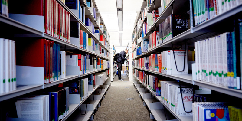 A man looking on shelves in library