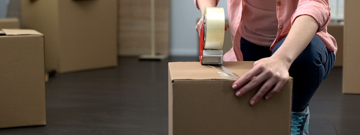 Packing for Uni 1200x450 - Person closing up cardboard boxes
