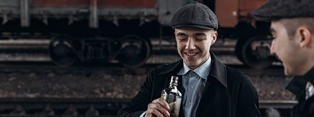 Peaky Blinders Response 1200x450 - Two men in peaky caps with alcohol